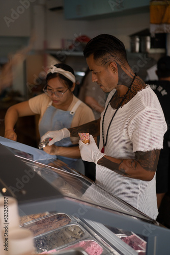 Young handsome mexican tattooed man making ice cream in a cone.