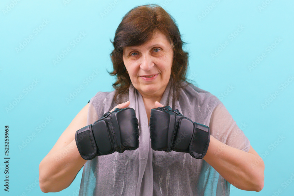 A woman facing two MMA gloves between each other on a blue background. Fighting. Combat. Conflict. Instruction. Box. Artist. Bald. Mixed Martial Arts
