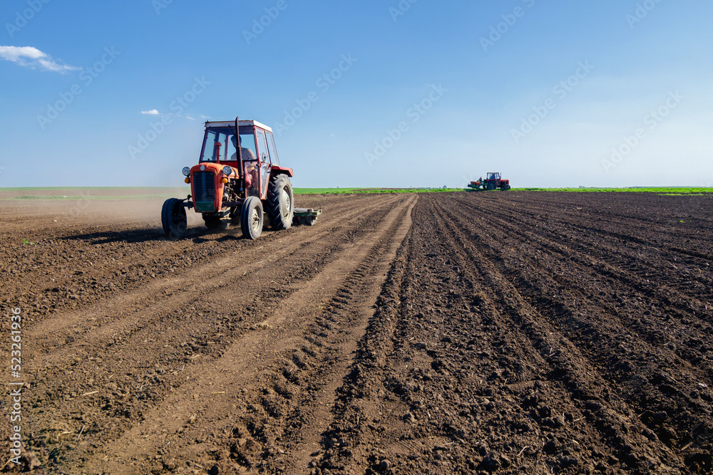 Farmer with tractor sowing on agricultural field on sunny spring day Farmer with tractor sowing on agricultural field on sunny spring day