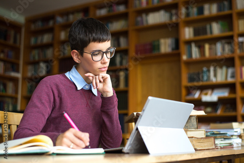 Young woman student reading books and studying in the library