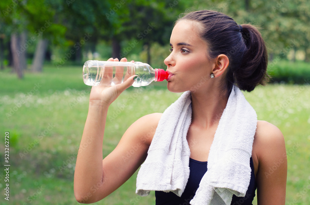 Young woman drinking water after exercise in summer nature Young woman drinking water after exercise in summer nature