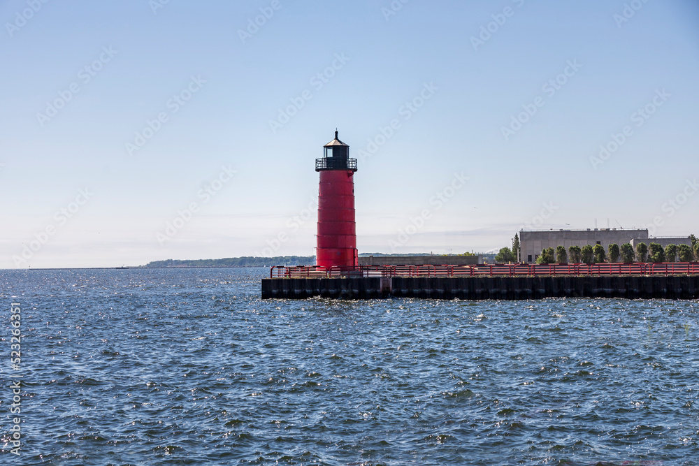 Red and black lighthouse on a jetty on a lake