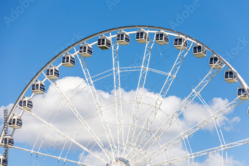 White and Black Ferris wheel in from of blue sky with clouds