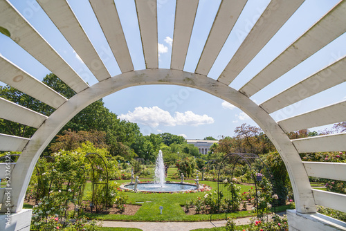 Wooden arch framing a fountain in the middle of a garden