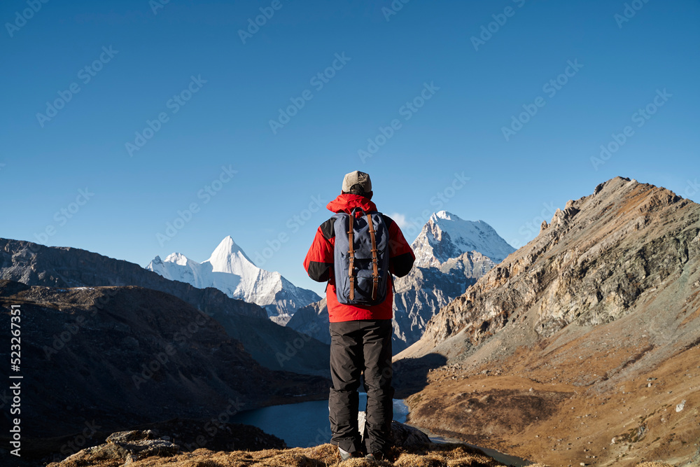 asian man backpacker male hiker looking at mountains in yading national park, china asian man backpacker male hiker looking at mountains in yading national park, china