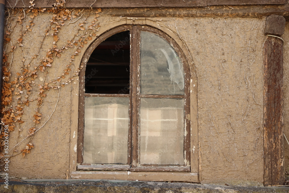 Arch window with broken glass in old building in europe