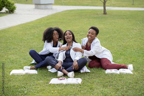students sitting on the lawn garden reading having fun wearing lab coat stethoscope
