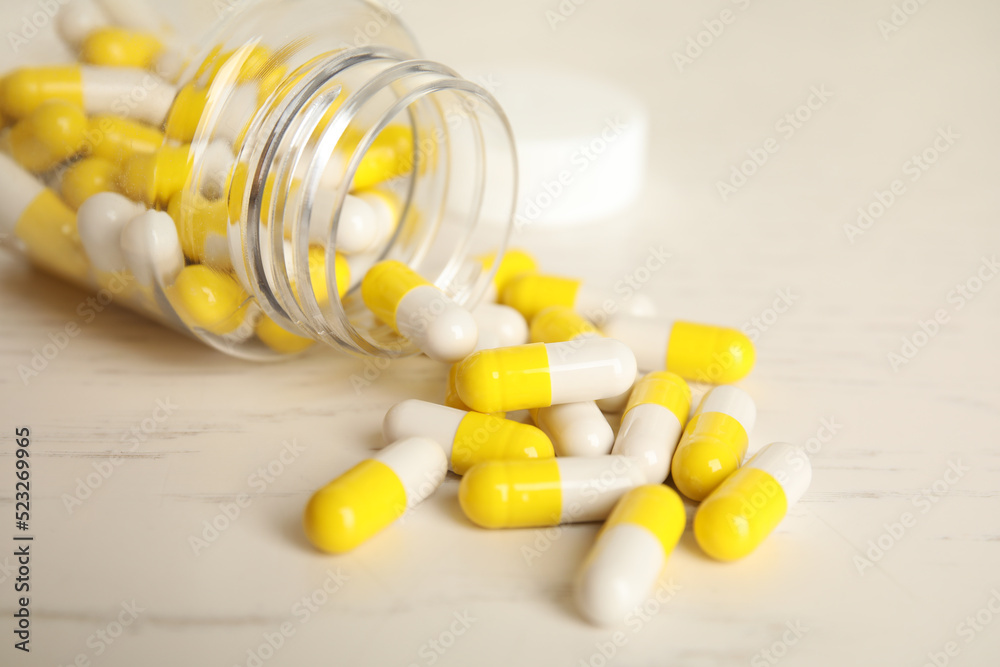 Bottle with vitamin pills on light table, closeup Bottle with vitamin pills on light table, closeup