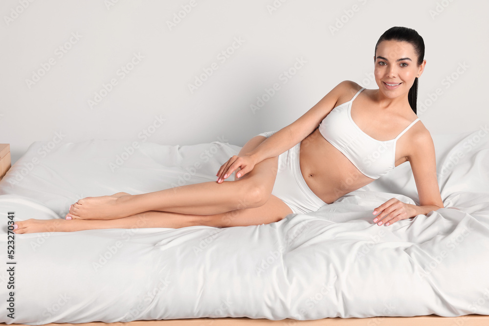 Young woman with beautiful smooth legs lying on bed at home Young woman with beautiful smooth legs lying on bed at home