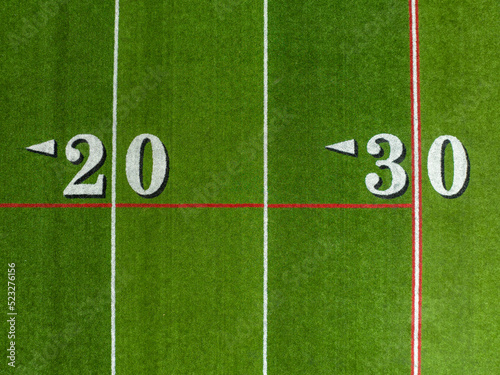 Aerial image of a typical synthetic turf football field 20 yard and 30 yard line in white. 