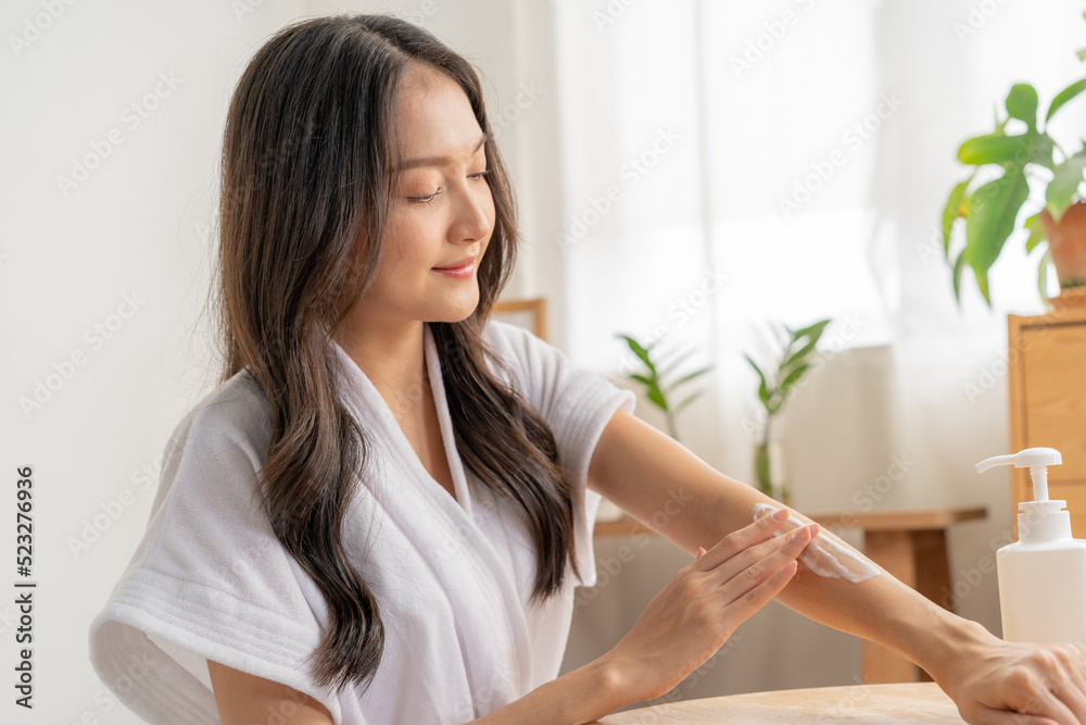 Healthy skin care, beauty asian young woman in bathrobe, towel after shower bath at home, hand in applying, putting moisturizer on her arm. Skin body cream moisturizing lotion, routine in the morning Healthy skin care, beauty asian young woman in bathrobe, towel after shower bath at home, hand in applying, putting moisturizer on her arm. Skin body cream moisturizing lotion, routine in the morning