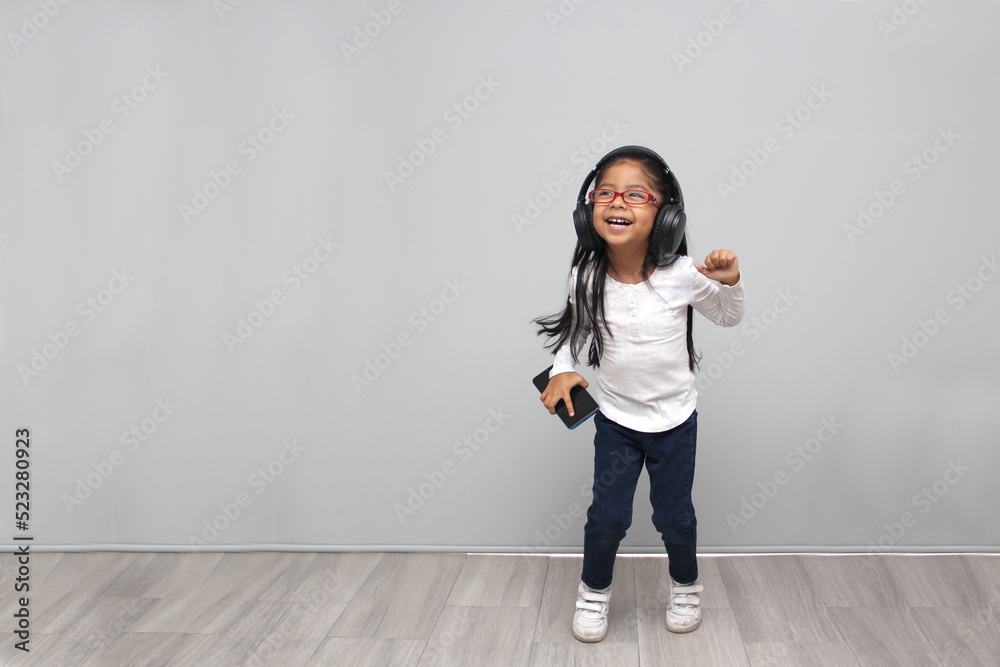 4-year-old brunette Latin girl with glasses listens to music in her headphones connected to her cell phone dances, sings and enjoys the rhythm happy and excited
4-year-old brunette Latin girl with glasses listens to music in her headphones connected to her cell phone dances, sings and enjoys the rhythm happy and excited