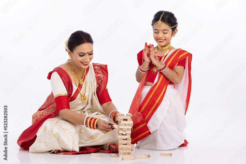 Foto de Happy bengali mother with daughter playing jenga together in