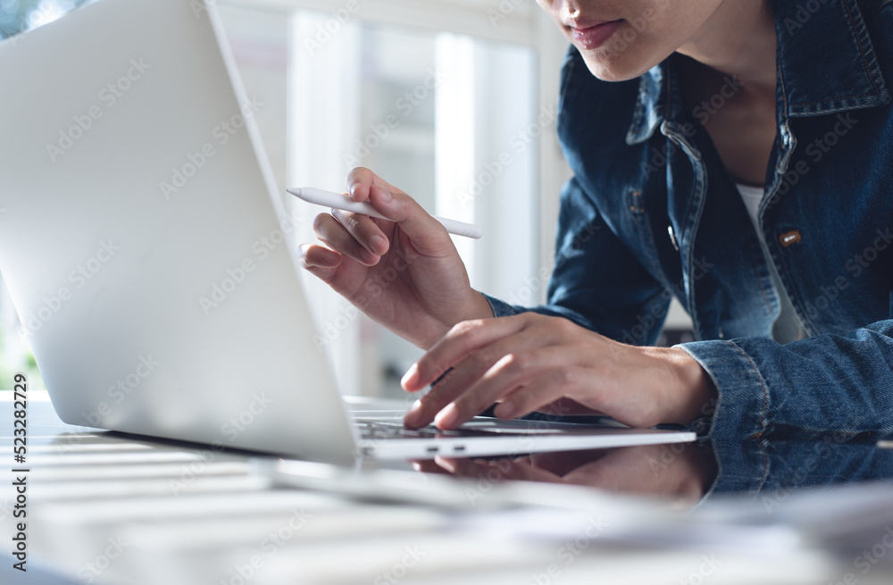 Fototapeta premium Asian business woman in smart casual wear sitting at table working on laptop computer at modern office at home, closeup. Student studying online class, e-learning, working at home