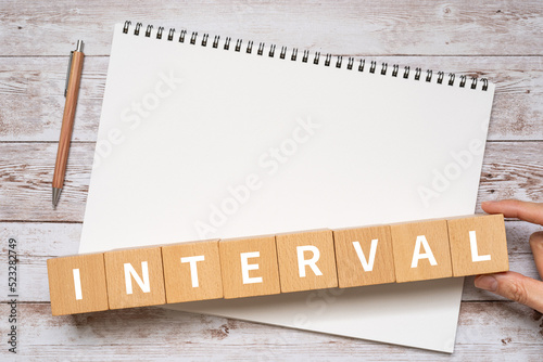インターバル・間隔のイメージ｜「INTERVAL」と書かれたブロック、ノート、ペン、手 
