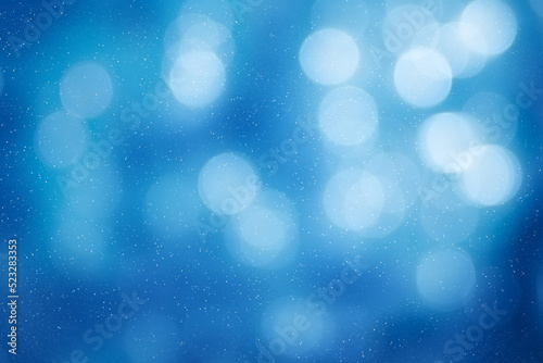 Blurred Soft White Bokeh against Light Blue. Snowing in a Beautiful Winter Sunny Day. © Baurzhan I