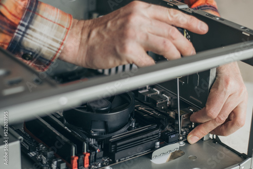 computer technician uses a screwdriver to fix the motherboard in the computer's system unit. the concept of computer equipment, repair, modernization and technologies. selective focus. close-up.