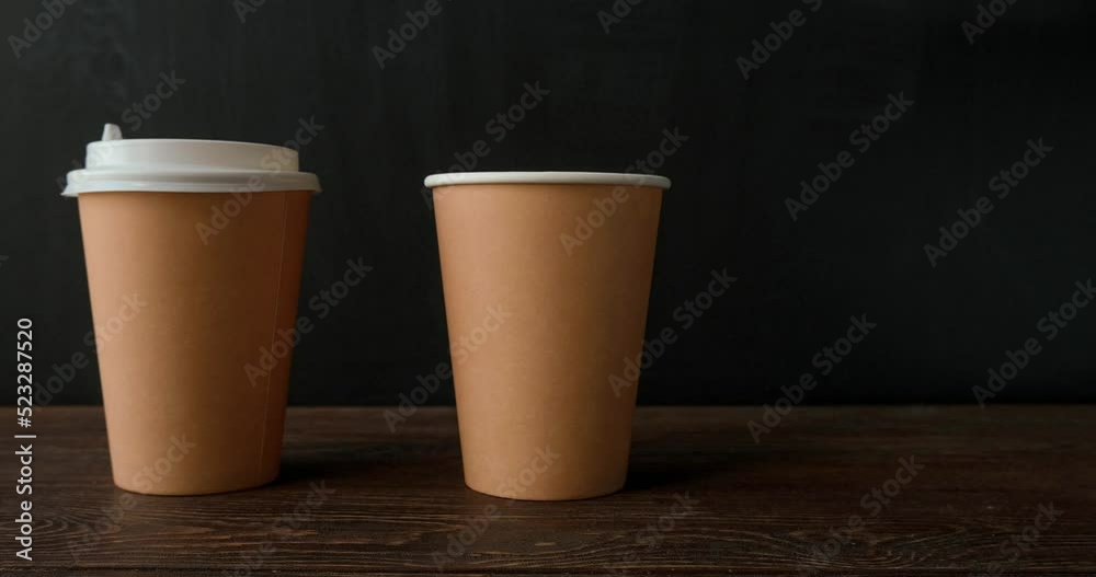 Paper cups and lids for coffee to go on a dark background. Looped 4K stop motion animation