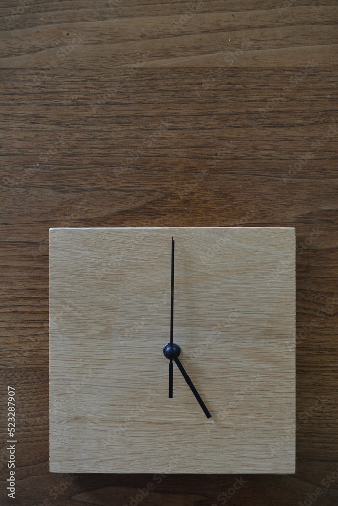 5時をしめしているシンプルな木製の掛け時計
