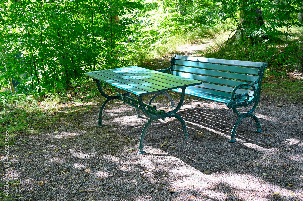green bench standing in a shaded area in garden green bench standing in a shaded area in garden