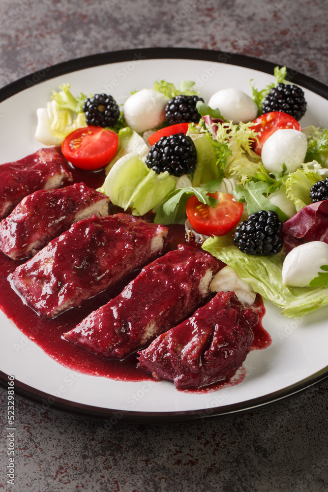 Blackberry Chicken with sweet, tart and savory blackberry butter sauce served with fresh salad closeup in the plate on the table. Vertical Blackberry Chicken with sweet, tart and savory blackberry butter sauce served with fresh salad closeup in the plate on the table. Vertical