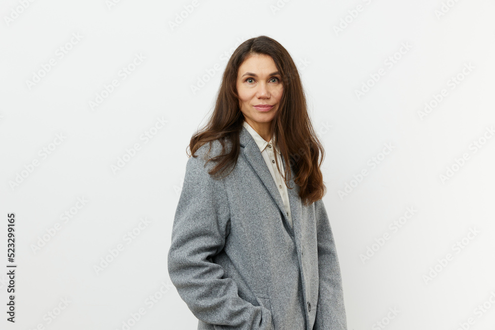 vertical portrait of a beautiful, sweet woman in a warm, stylish, autumn coat smiling pleasantly at the camera while standing against a light background vertical portrait of a beautiful, sweet woman in a warm, stylish, autumn coat smiling pleasantly at the camera while standing against a light background