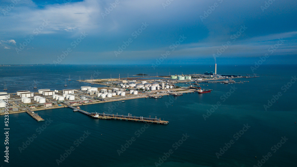 Aerial view oil terminal and coal power plant station in sea, White oil storage tank chemical petroleum petrochemical refinery product, Tanker ship at deep ocean seaport terminal.