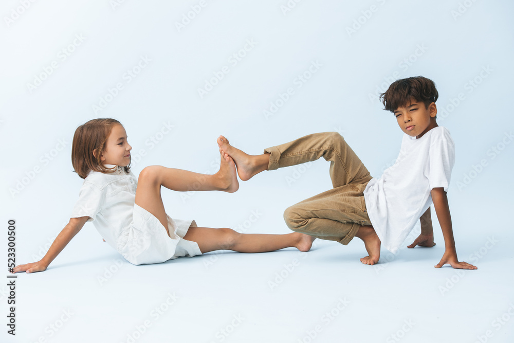 Funny boy and girl pressing feet against one another's on the floor