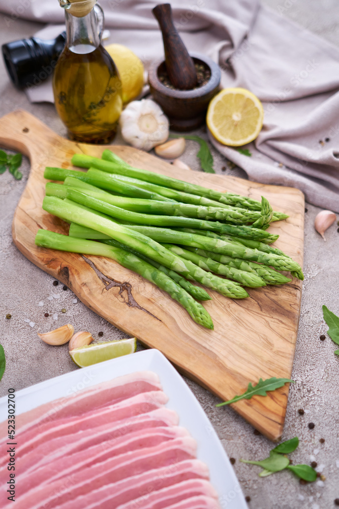 Green organic natural Asparagus on wooden cutting board and slice bacon at kitchen table Green organic natural Asparagus on wooden cutting board and slice bacon at kitchen table