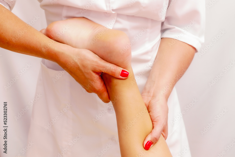 Fototapeta premium Young woman getting a massage at the spa. Body care. Therapeutic foot massage in the spa salon. Skin care, well-being