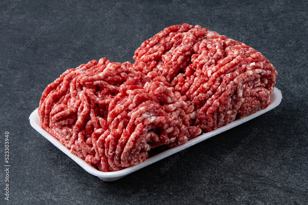 Fresh raw minced beef on backing paper over dark gray cement background