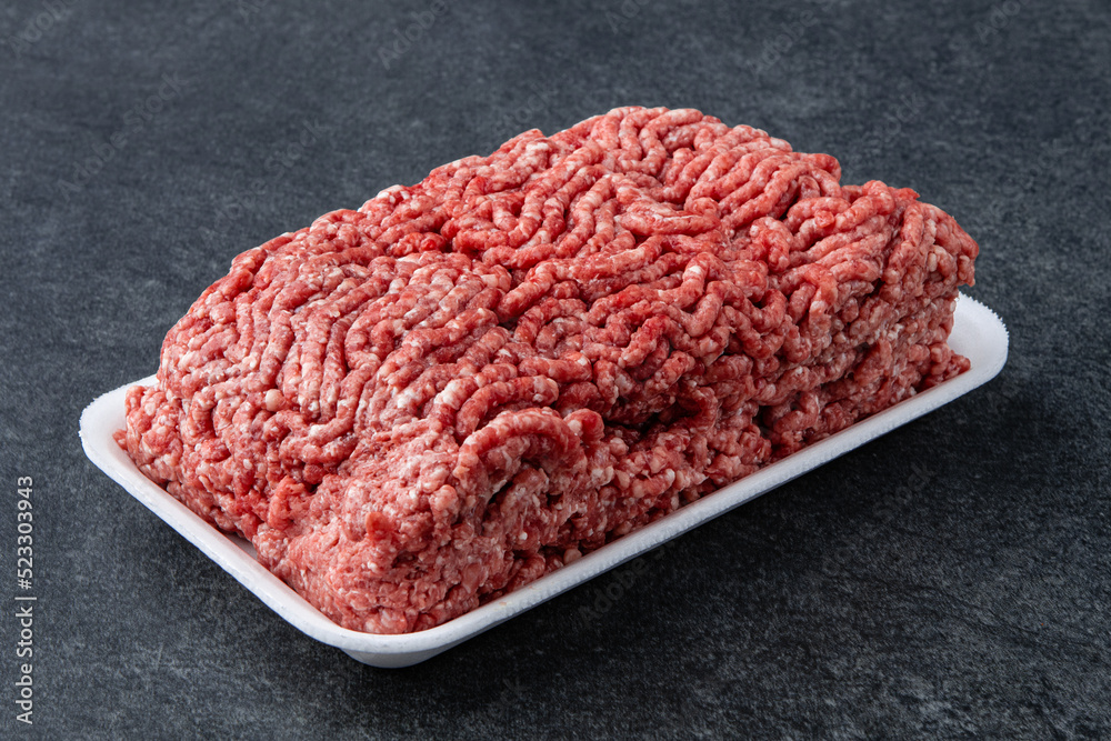 Fresh raw minced beef on backing paper over dark gray cement background Fresh raw minced beef on backing paper over dark gray cement background