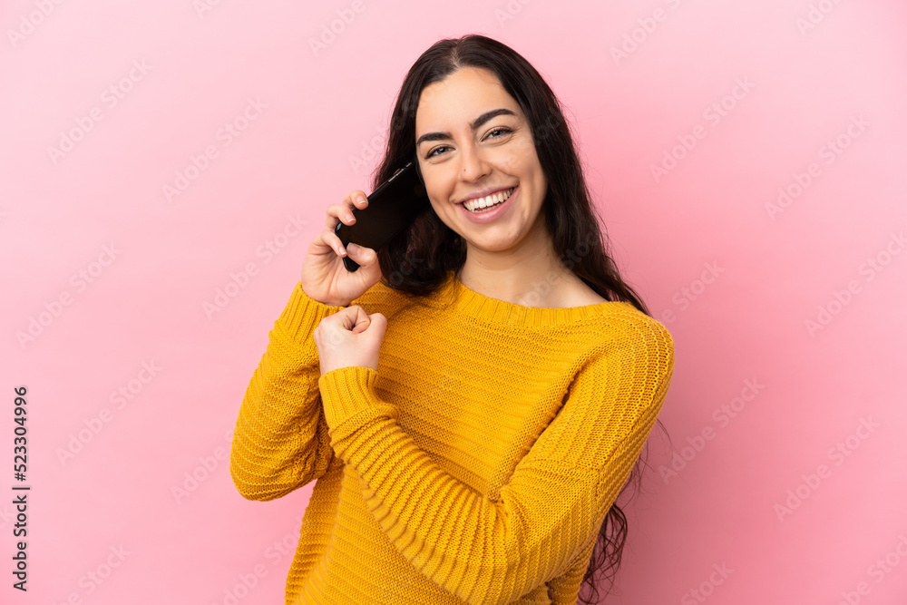 Young caucasian woman using mobile phone isolated on pink background celebrating a victory Young caucasian woman using mobile phone isolated on pink background celebrating a victory