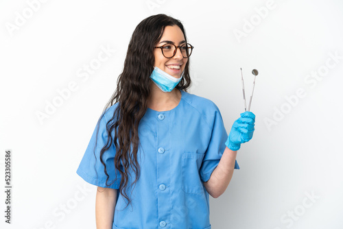 Young woman dentist holding tools isolated on white background looking side