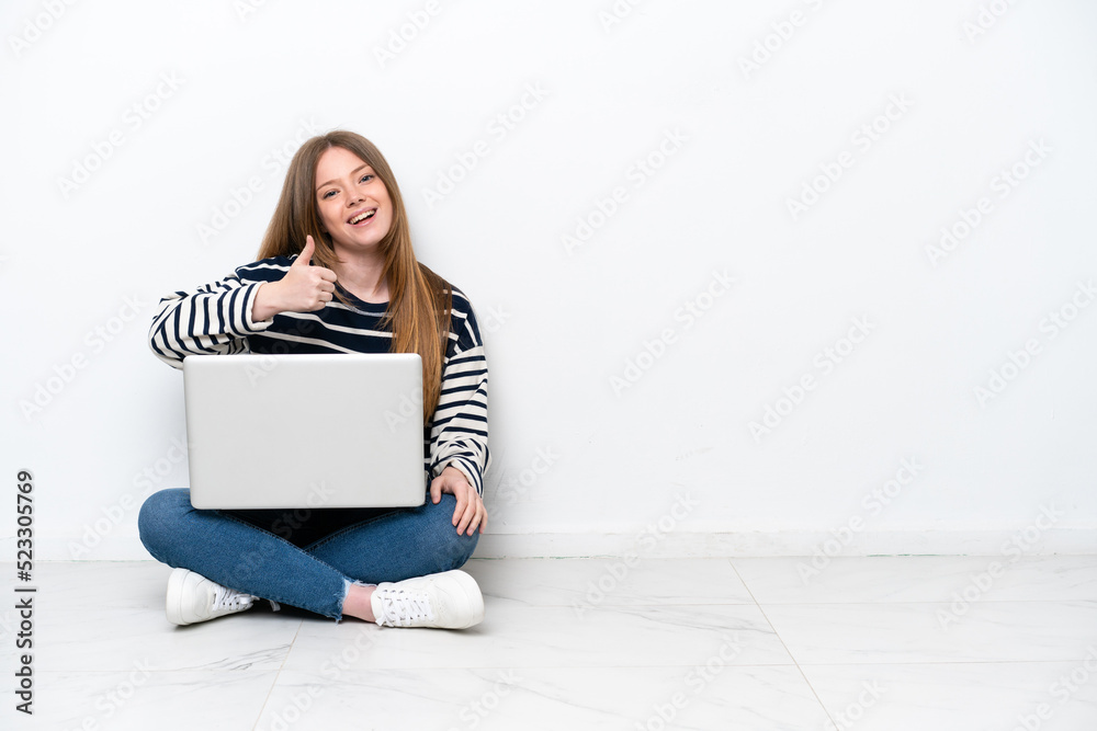Young caucasian woman with a laptop sitting on the floor isolated on white background with thumbs up because something good has happened Young caucasian woman with a laptop sitting on the floor isolated on white background with thumbs up because something good has happened