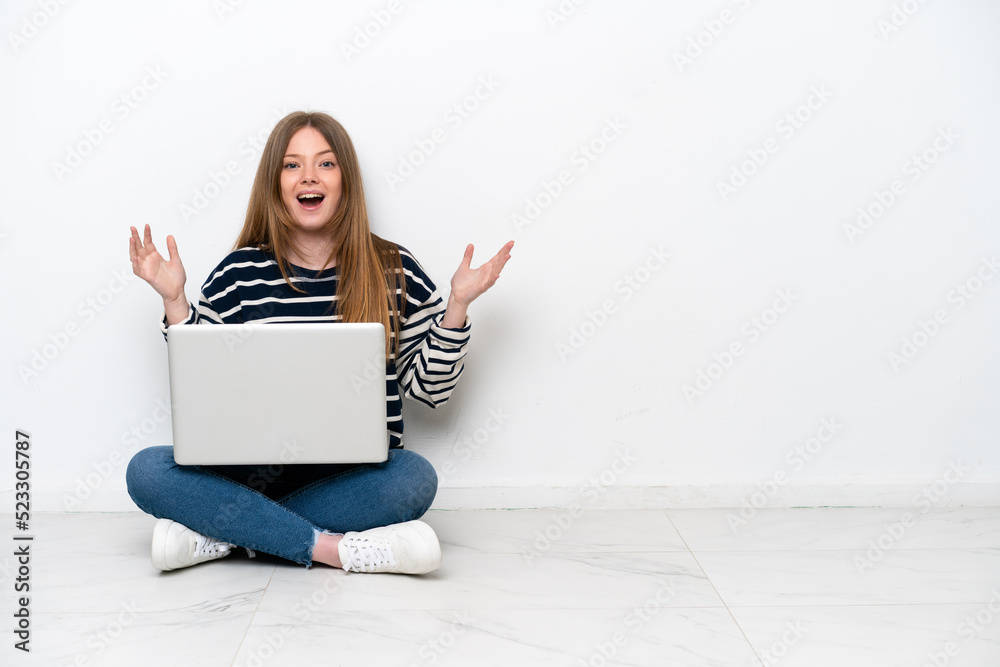 Young caucasian woman with a laptop sitting on the floor isolated on white background with surprise facial expression Young caucasian woman with a laptop sitting on the floor isolated on white background with surprise facial expression