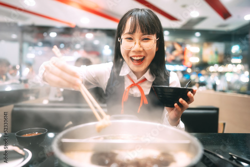 Fotografie Happy young asian woman japanese thai student eating shabu japan sukiyaki restaurant