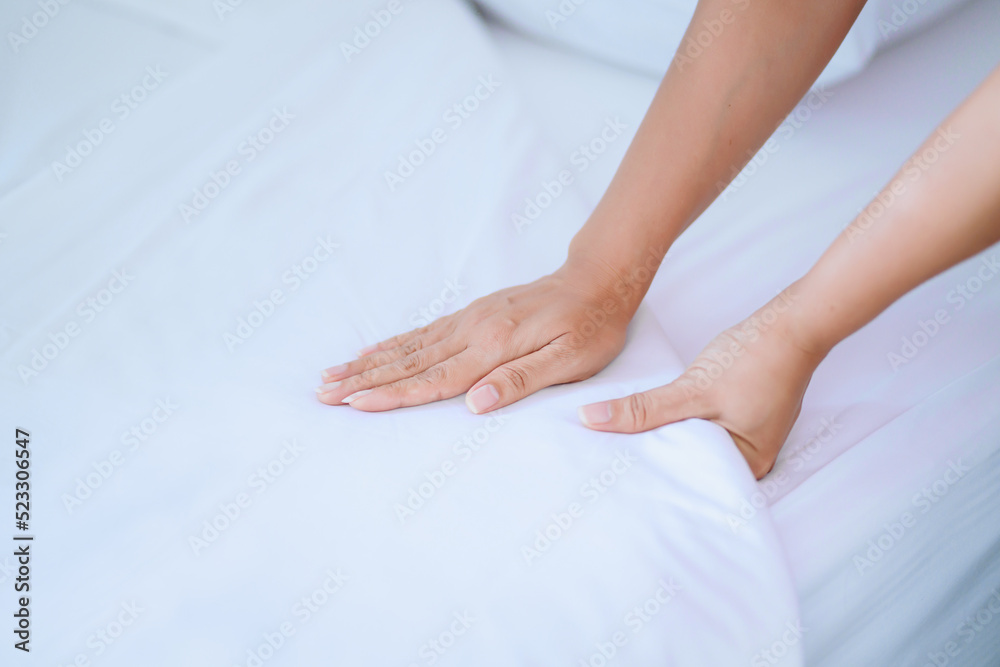 Female Hand set up white bed sheet in bedroom or maid hands making bed in a hotel room