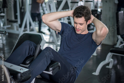 Handsome man exercising doing sit up abdominal exercise in gym