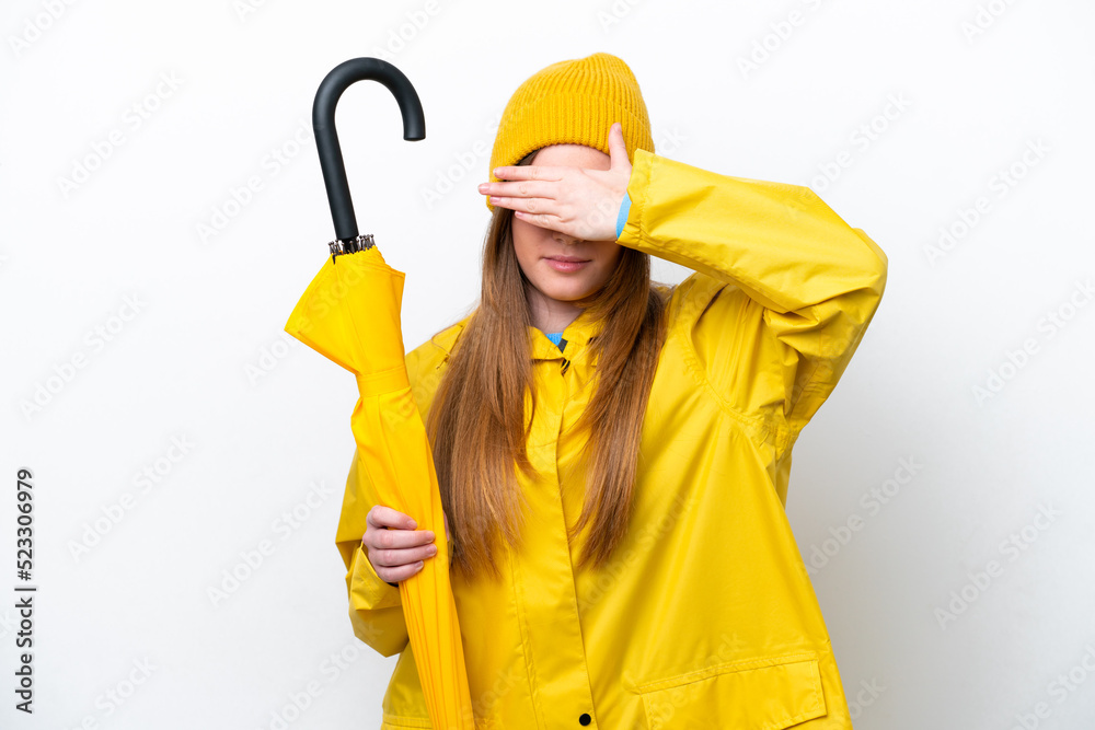 Young caucasian woman with rainproof coat and umbrella isolated on white background covering eyes by hands. Do not want to see something Young caucasian woman with rainproof coat and umbrella isolated on white background covering eyes by hands. Do not want to see something