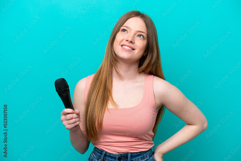 Singer caucasian woman picking up a microphone isolated on blue background thinking an idea while looking up Singer caucasian woman picking up a microphone isolated on blue background thinking an idea while looking up
