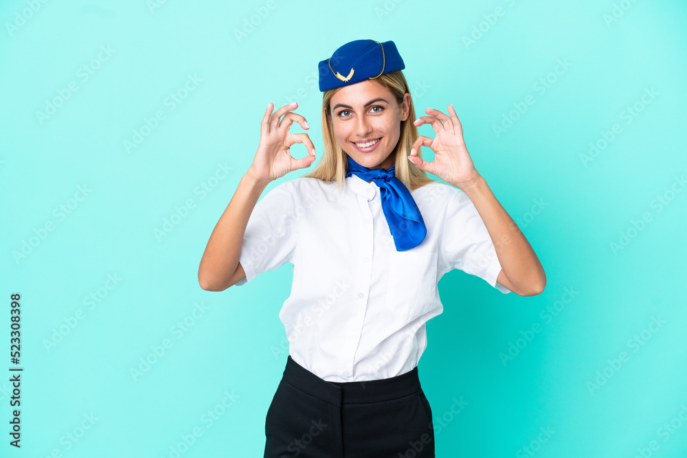 Airplane stewardess Uruguayan woman isolated on blue background showing an ok sign with fingers Airplane stewardess Uruguayan woman isolated on blue background showing an ok sign with fingers