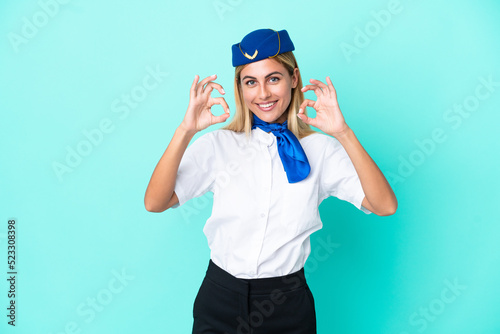 Airplane stewardess Uruguayan woman isolated on blue background showing an ok sign with fingers