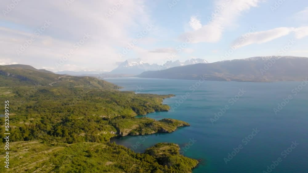 Aerial Shot Of Snowcapped Mountains By Lake Under Cloudy Sky, Drone Flying Forward Over Green Landscape - Paine, Chile