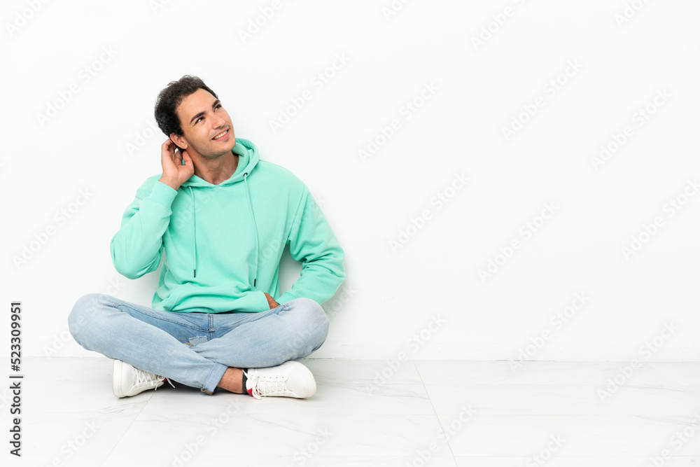 Caucasian handsome man sitting on the floor thinking an idea
