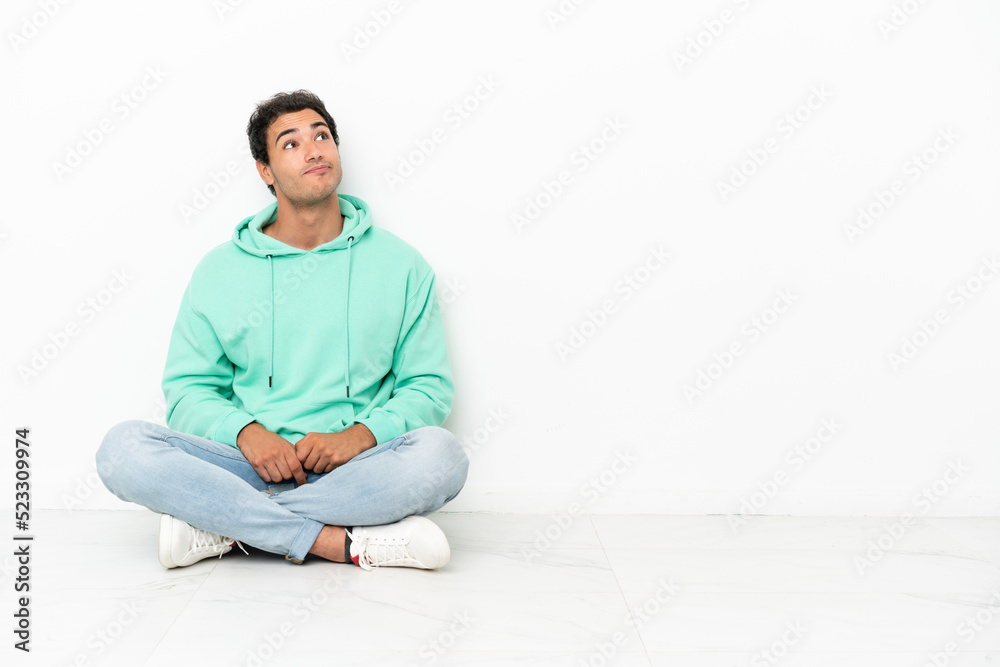 Caucasian handsome man sitting on the floor and looking up Caucasian handsome man sitting on the floor and looking up