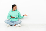 Caucasian handsome man sitting on the floor with surprise facial expression