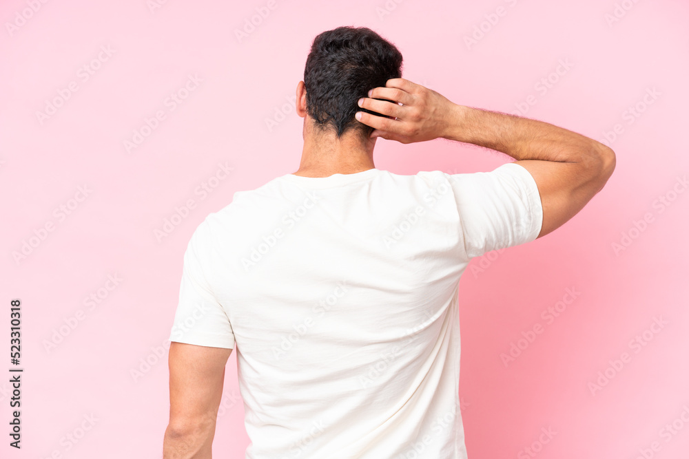Young caucasian man isolated on pink background in back position and thinking Young caucasian man isolated on pink background in back position and thinking