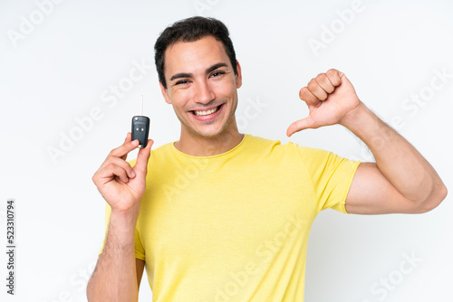 Young caucasian man holding car keys isolated on white background proud and self-satisfied