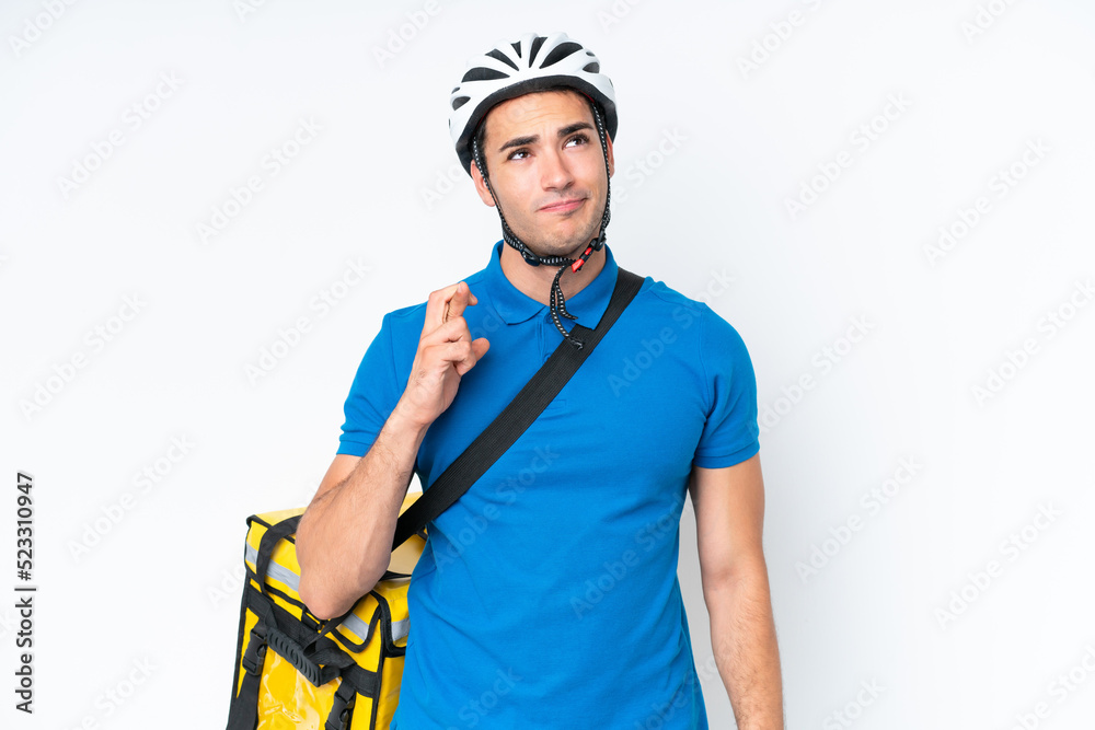 Young caucasian man with thermal backpack isolated on white background with fingers crossing and wishing the best Young caucasian man with thermal backpack isolated on white background with fingers crossing and wishing the best
